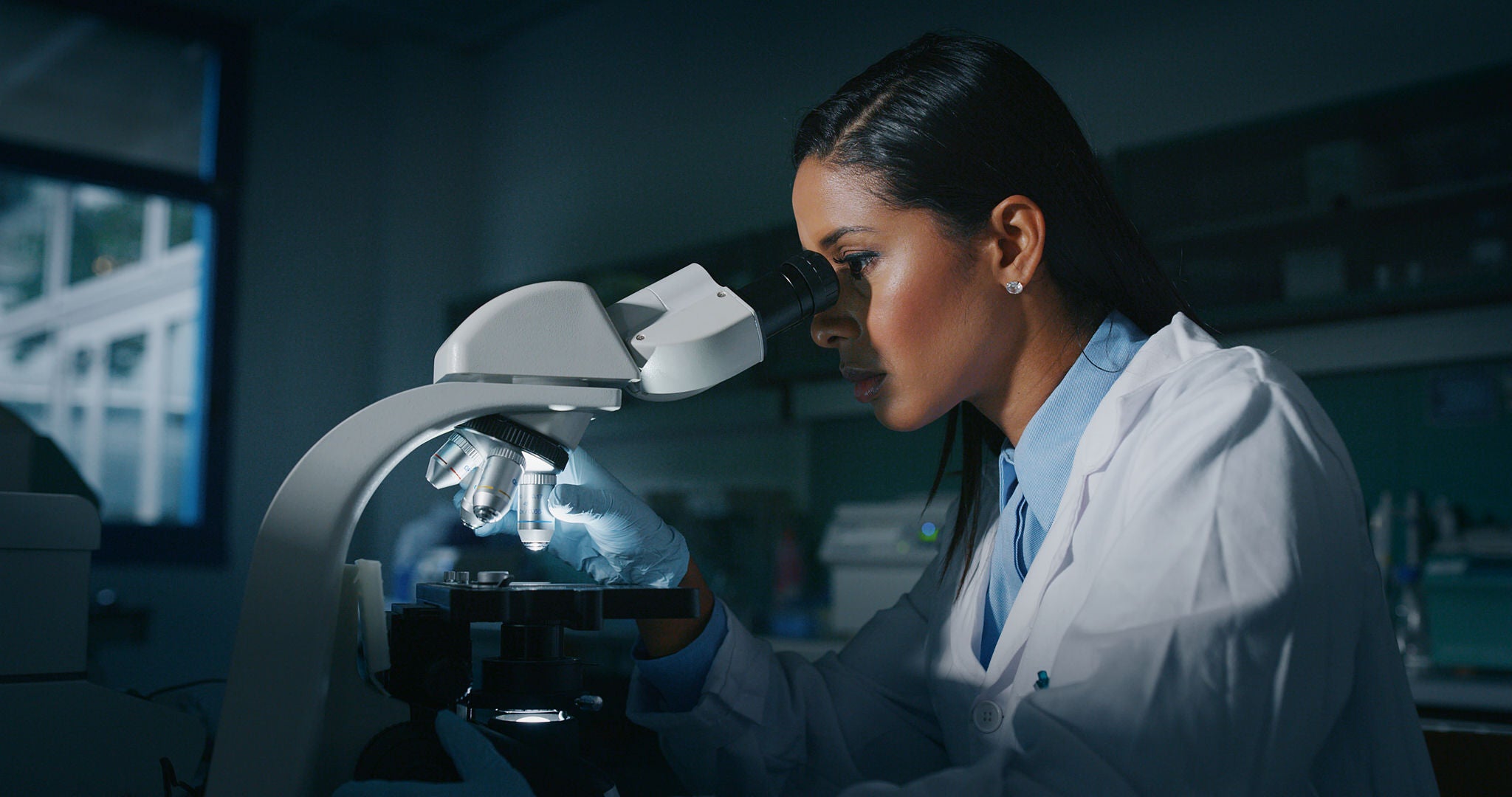 Portrait of dark skin female scientist is analyzing a sample to extract the DNA and molecules with microscope in laboratory.