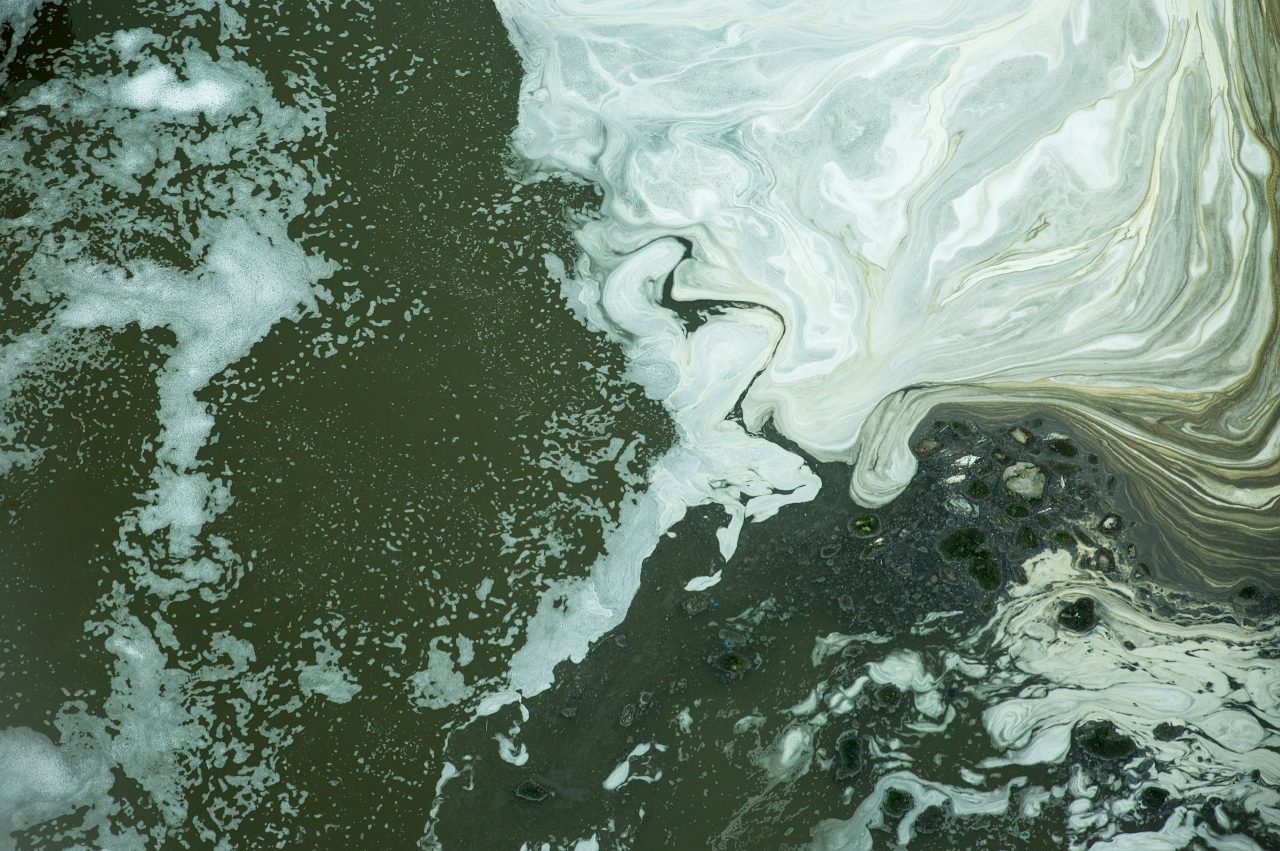 Black water with white bubbles in the wastewater treatment pond